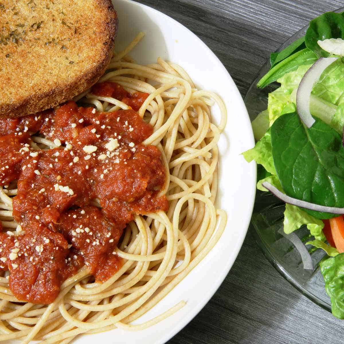 A plate of spaghetti and meatballs, and a salad.