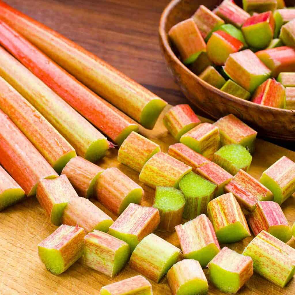 Six rhubarb stalks being chopped and put in a bowl.