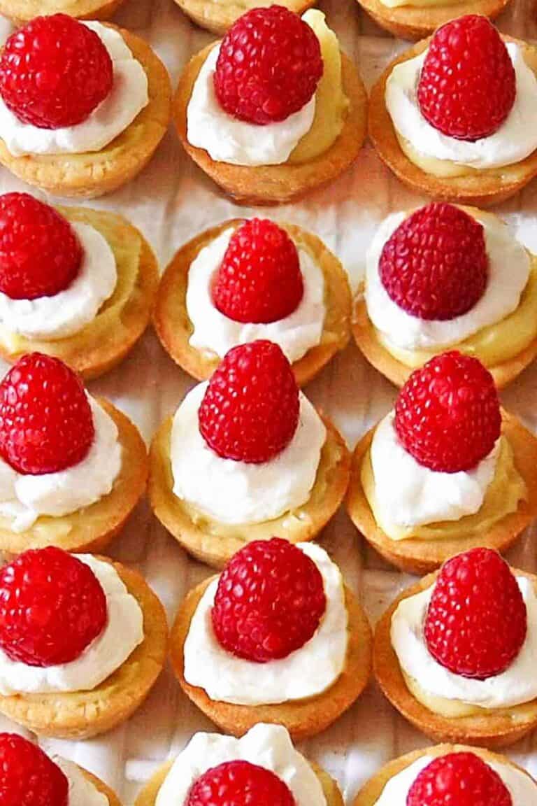 Mini raspberry custard tarts lined up on a serving platter.
