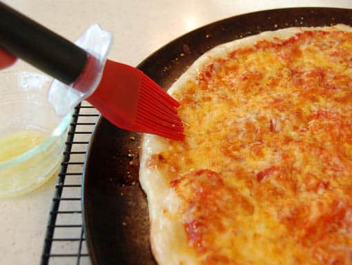 Brushing pizza crust with garlic butter at HappySimpleLiving.com