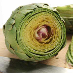 A raw artichoke with the top cut off, ready to be steamed in the microwave.