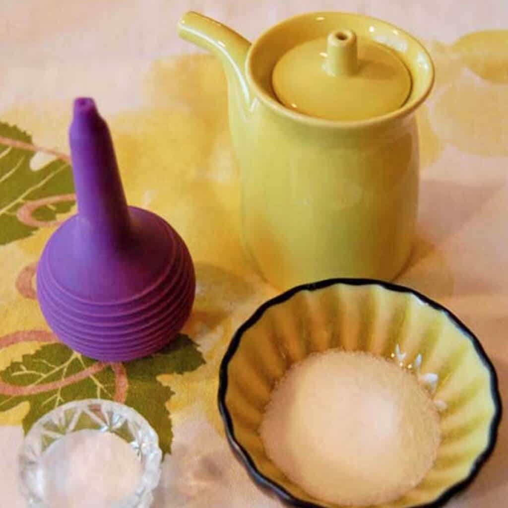 A small green pitcher, dish of salt, dish of baking soda and nasal wash bulb.