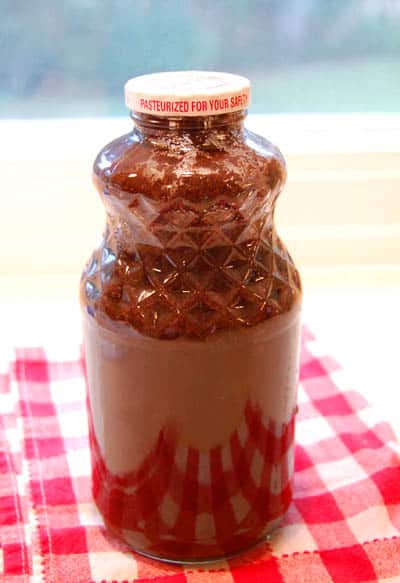 A glass jar full of coffee concentrate and steeping the coffee in water.