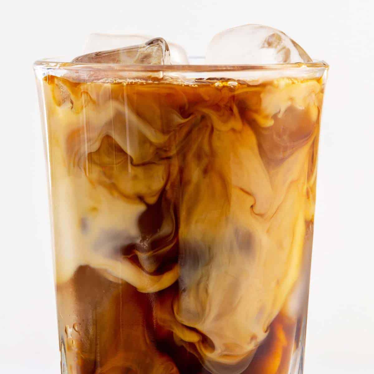 A glass filled with iced coffee and ice.
