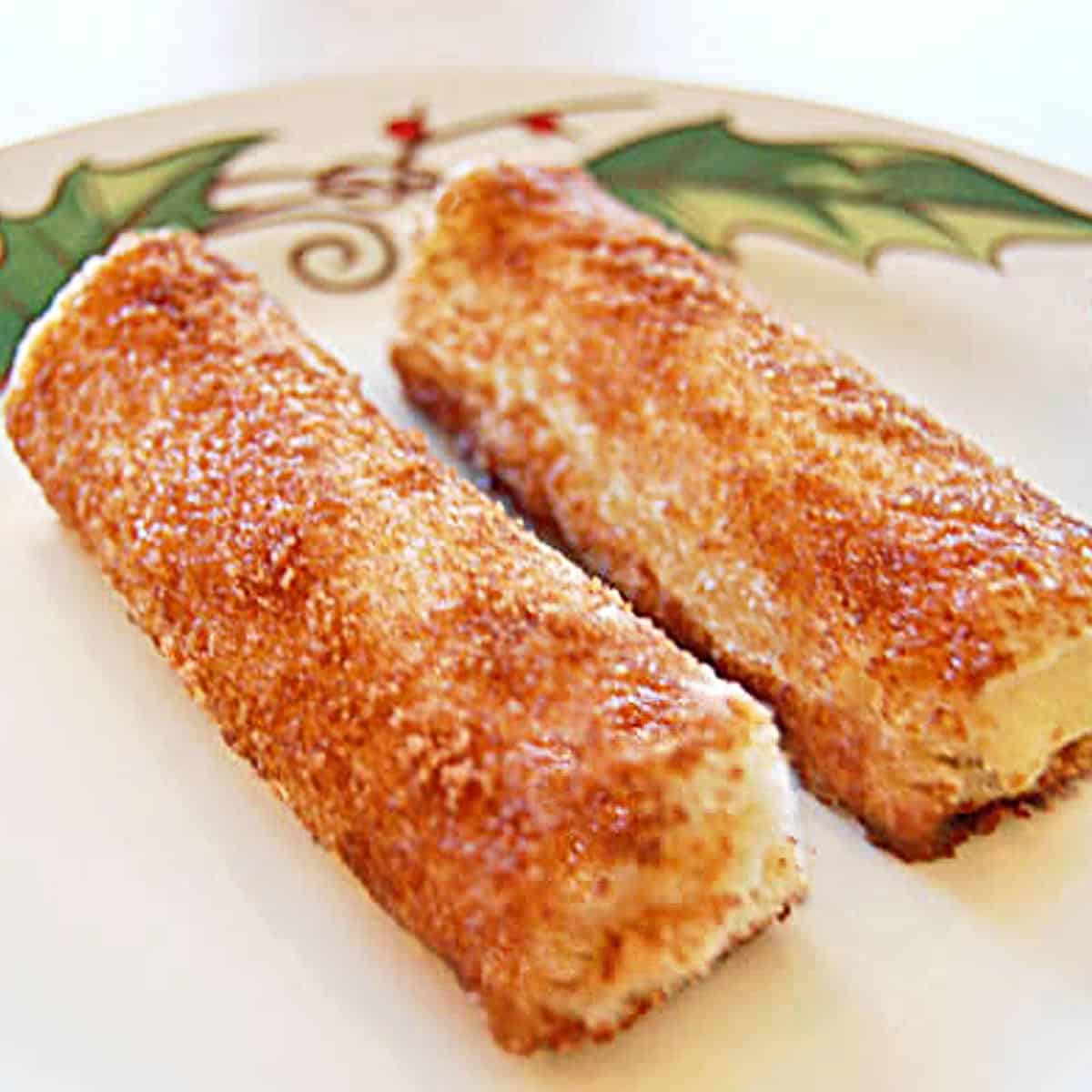 Two cream cheese roll ups on a green and white plate.