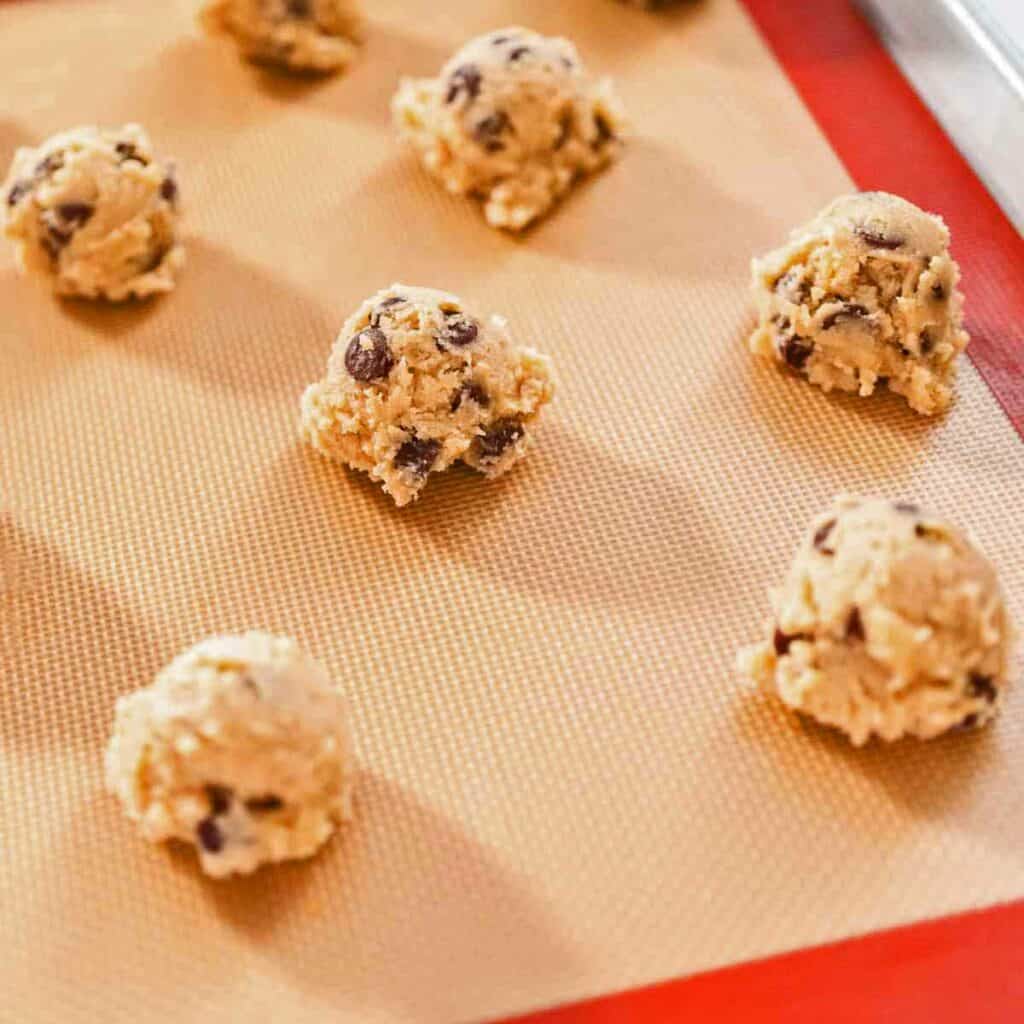 Cookie dough balls on a silicone baking mat.