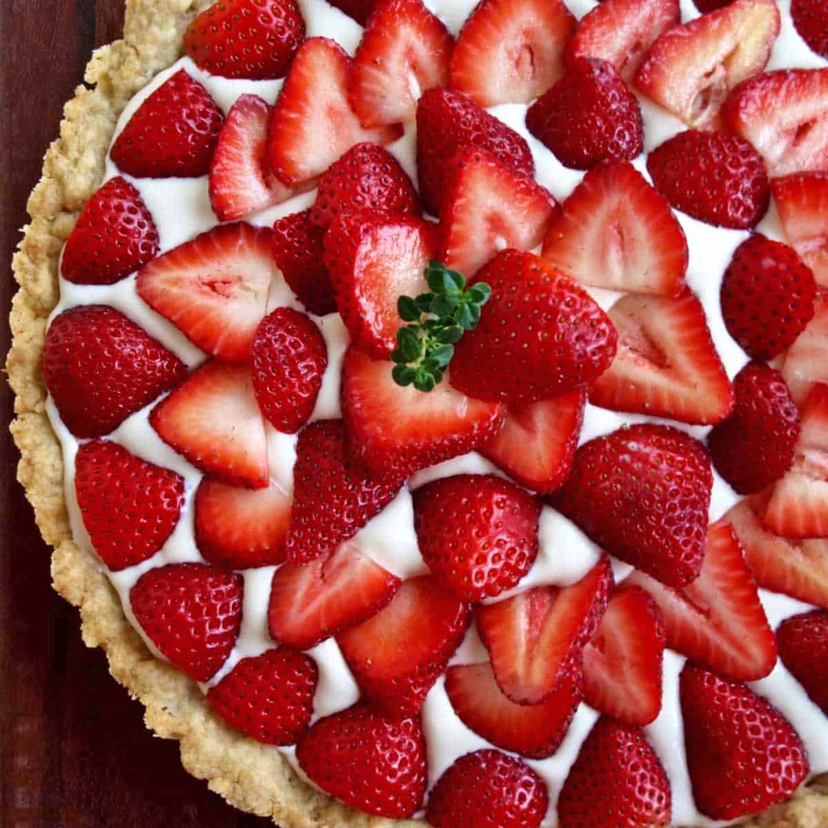 Close up of a strawberry cream tart with shortbread crust and a creamy whipped cream filling.