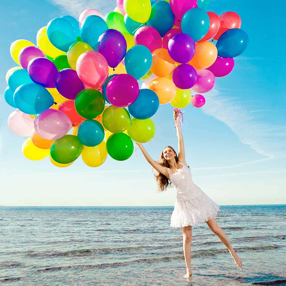 A woman holding a group of colorful balloons.