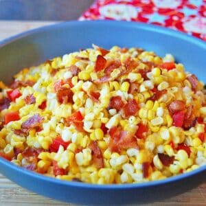 A large skillet filled with fried corn with bacon.