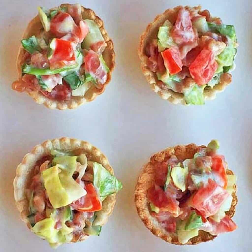 Four mini BLT cup appetizers on a white background.