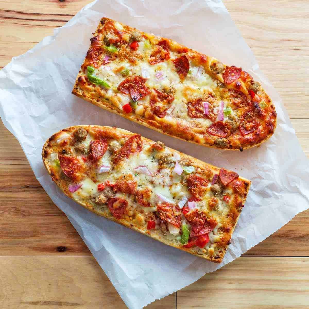 Two half loaves of French bread pizza with melted cheese and toppings.