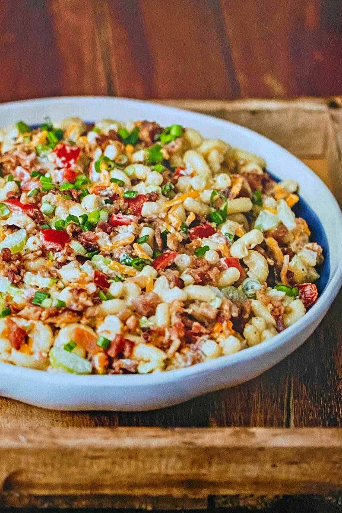 A white bowl filled with macaroni salad with bacon.