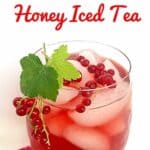 A glass of red currant honey iced tea garnished with currant leaves and berries.