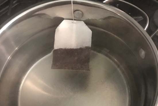 Making honey iced tea with tea bags and boiling water in a saucepan.