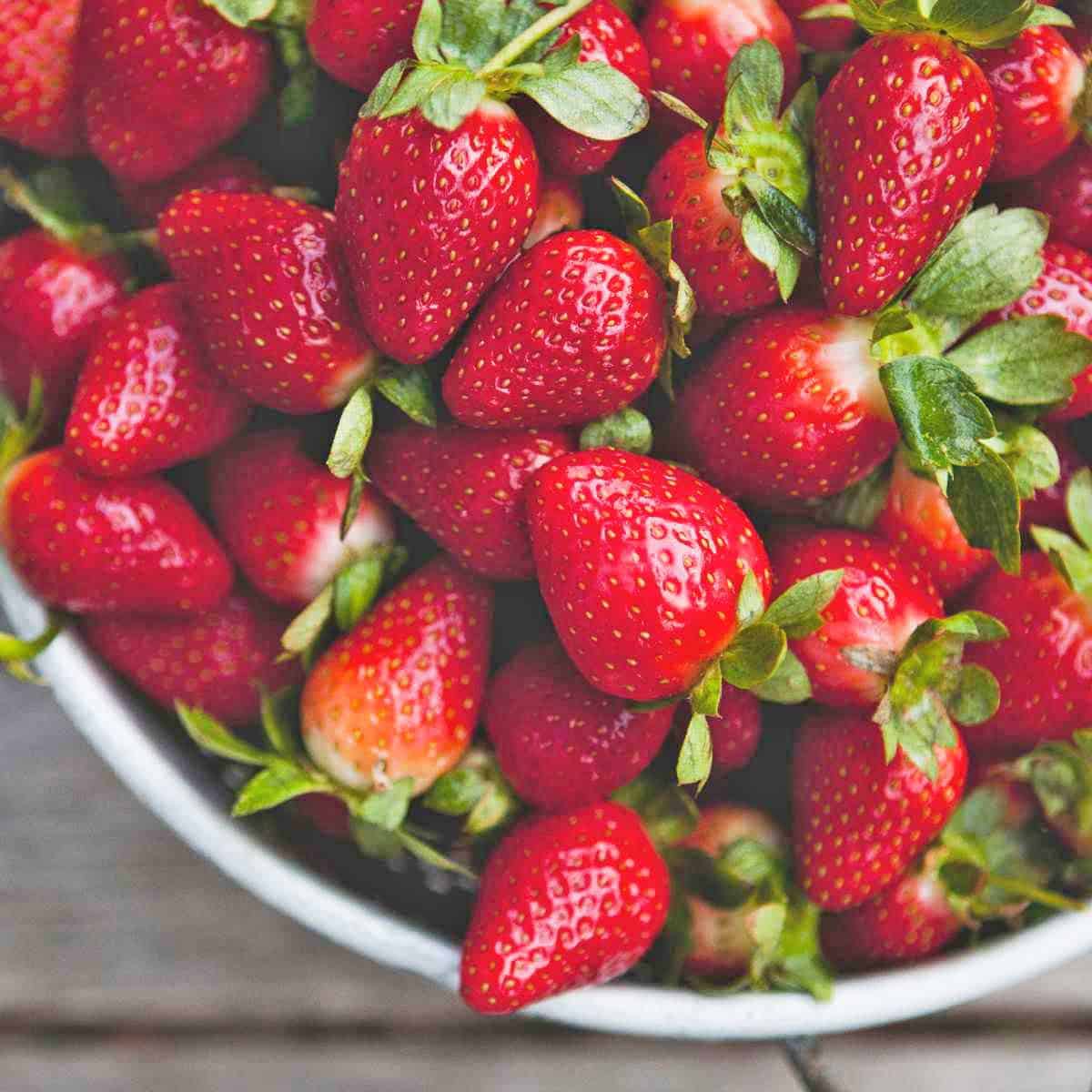 A metal strainer filled with fresh strawberries.