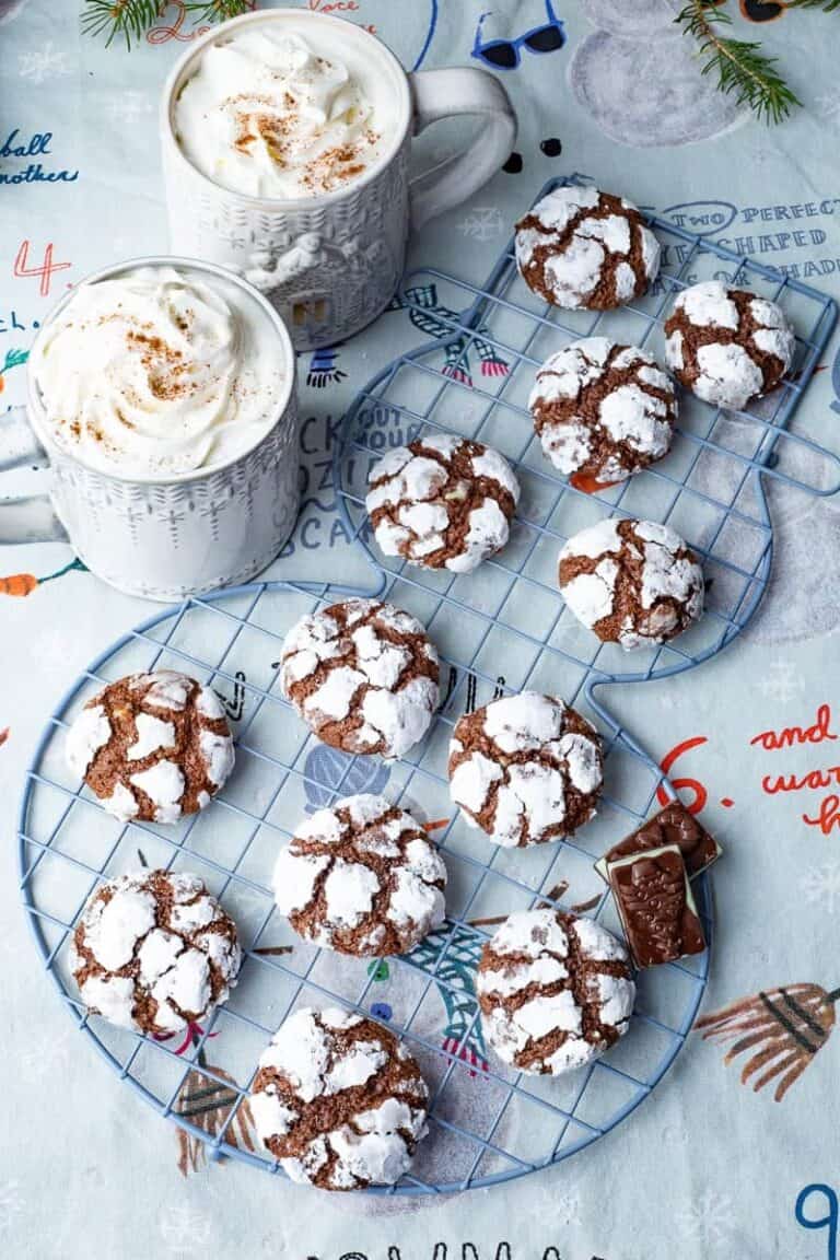 Chocolate crinkle cookies on a serving platter with hot chocolate nearby.