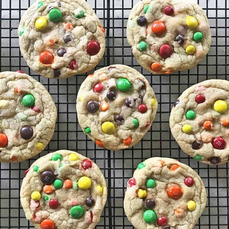 Seven chewy M & M cookies on a cooling rack.