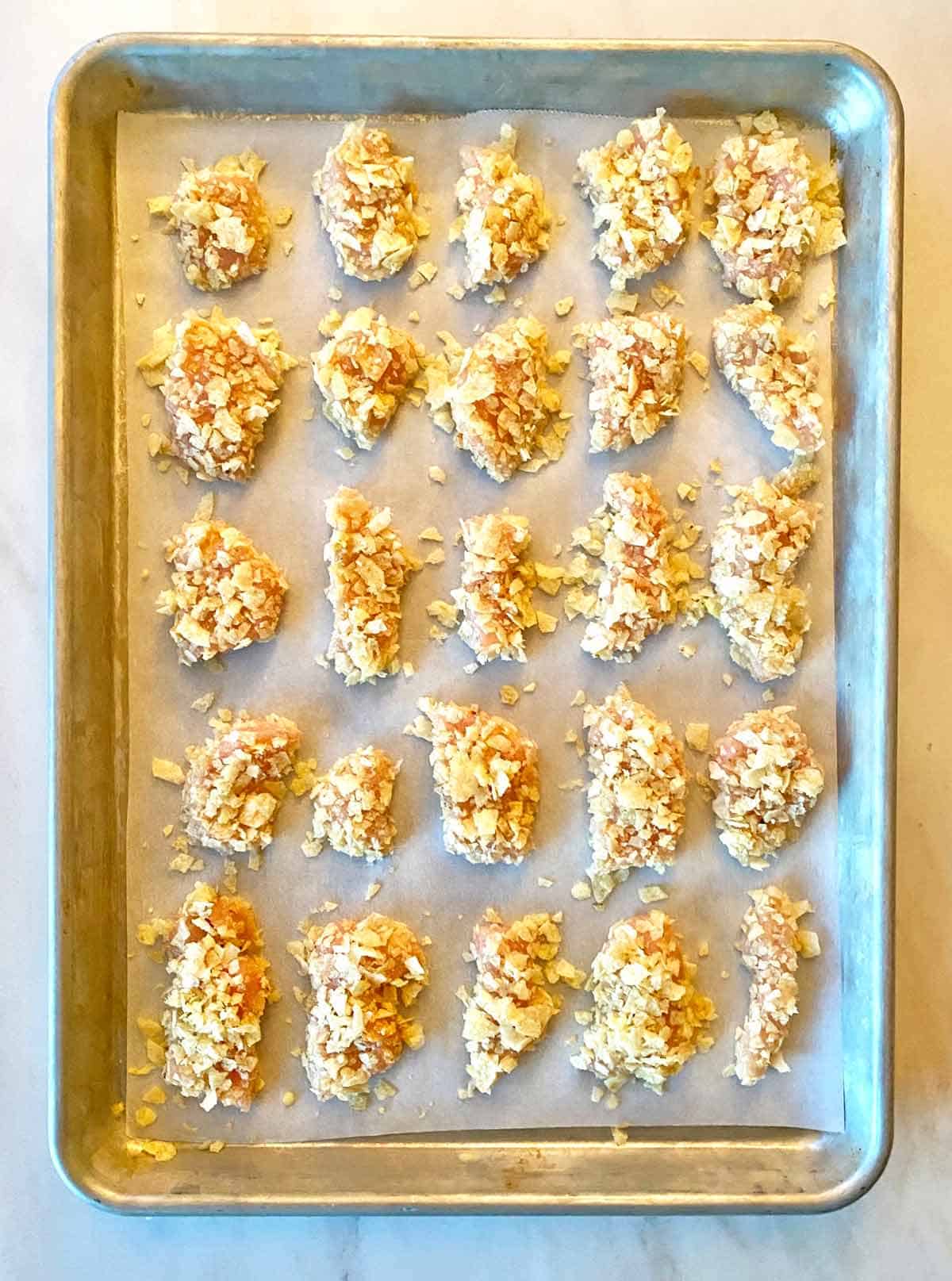 Uncooked potato chip nuggets on a baking sheet.