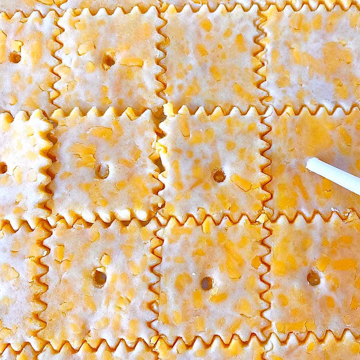 Poking holes with a skewer in cut cheese crackers dough.