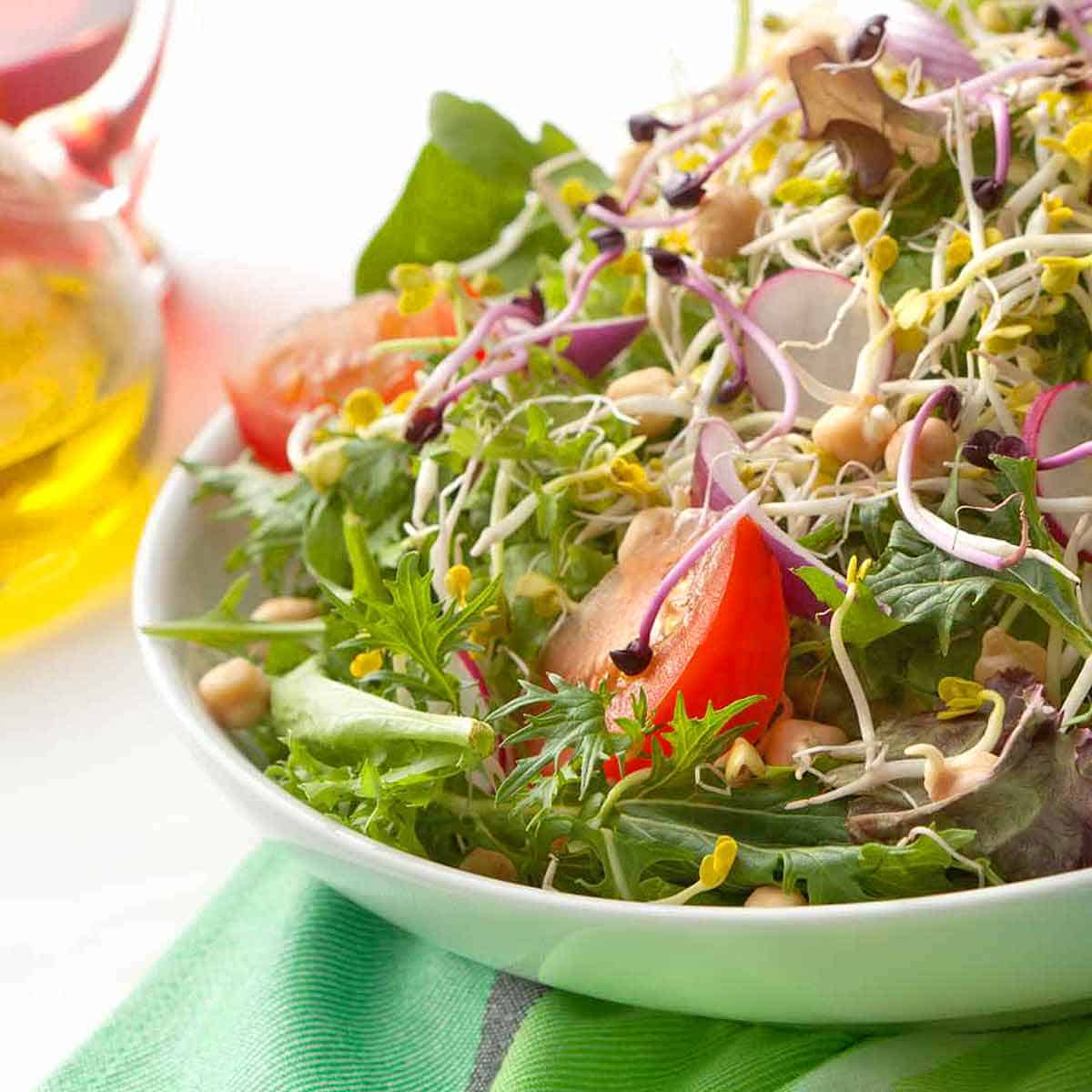 A fresh green salad topped with sprouts.