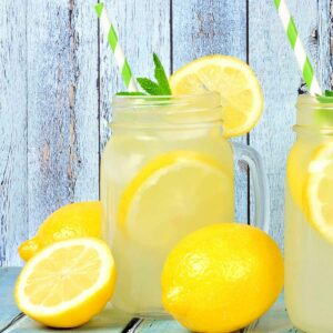 A glass of fresh, ice cold homemade lemonade garnished with lemon slices and fresh mint sprigs.