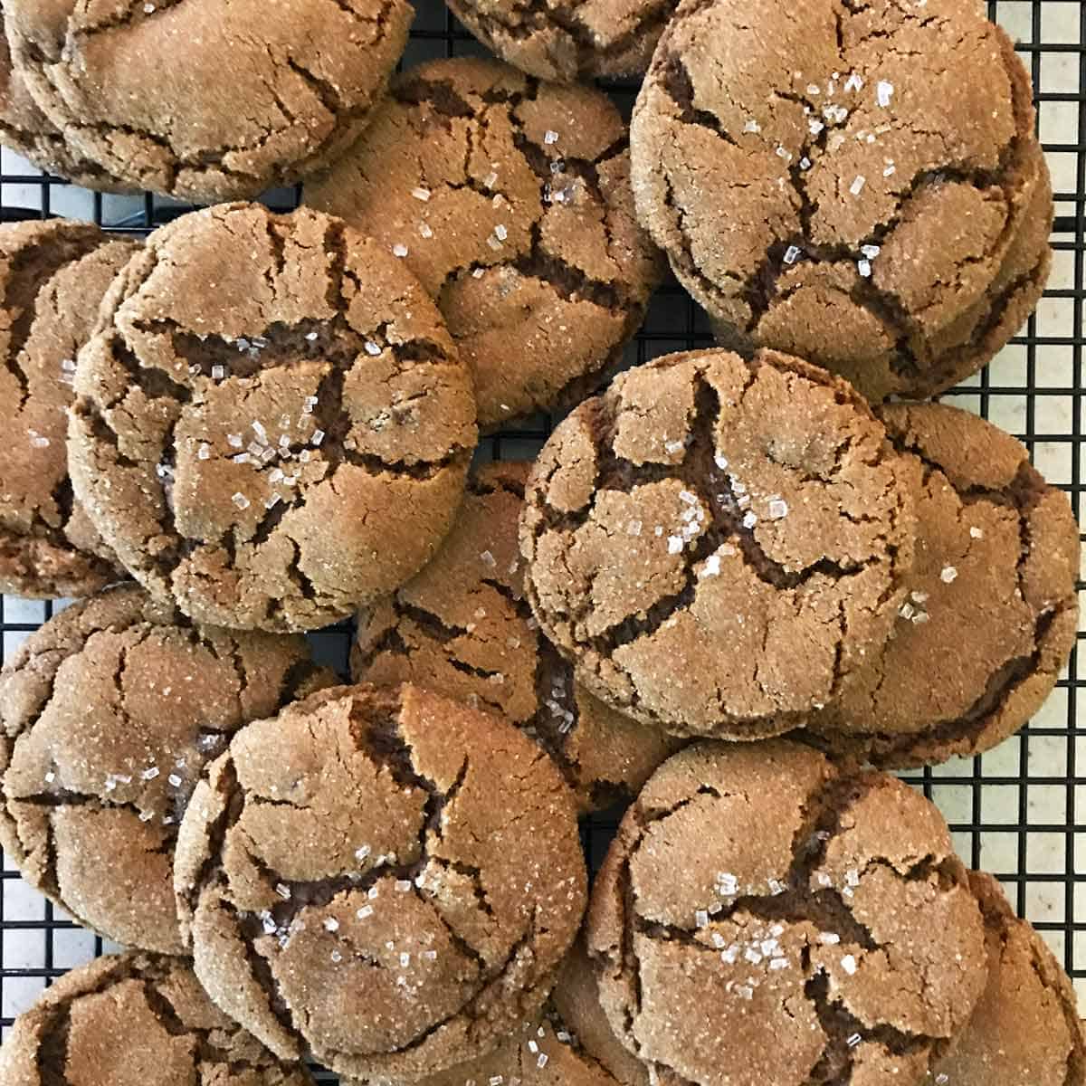 Baked molasses cookies with crinkled tops on a cooling rack.