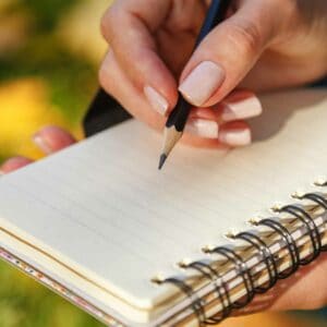 A woman's hand with a pencil on a journal.