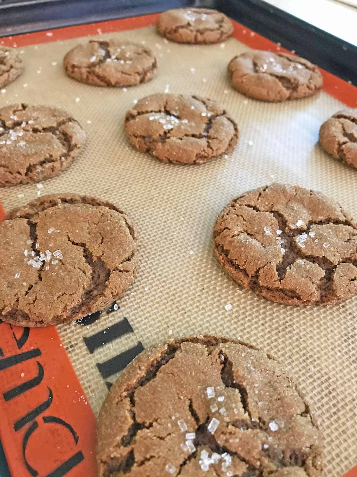 Chewy molasses cookies on a baking sheet with a silpat.