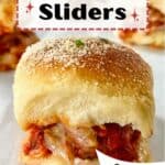 A meatball slider with melted cheese and sprinkled with Parmesan cheese.