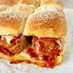Close up of just-baked Italian meatball sliders sprinkled with grated Parmesan cheese.