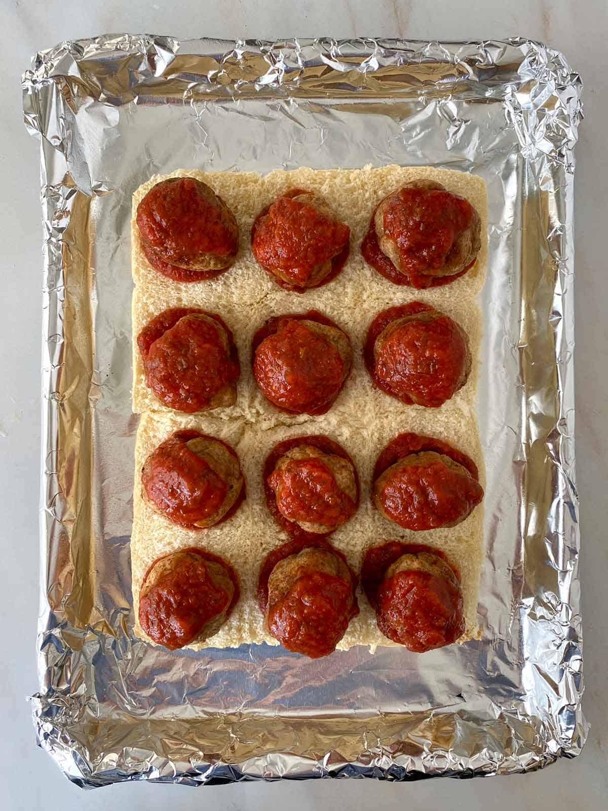 12 meatballs topped with marinara sauce for slider sandwiches.