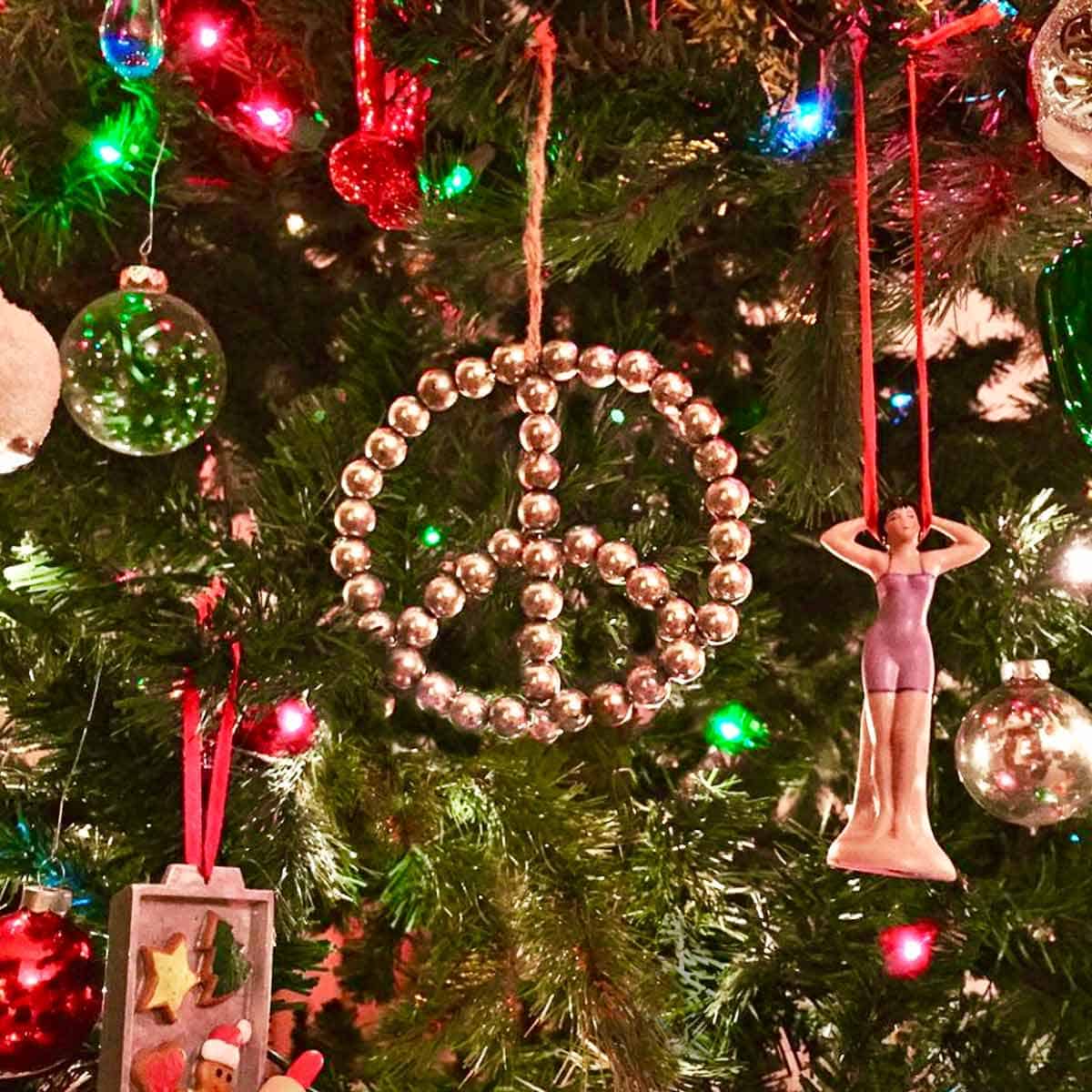A peace sign ornament on a decorated Christmas tree.