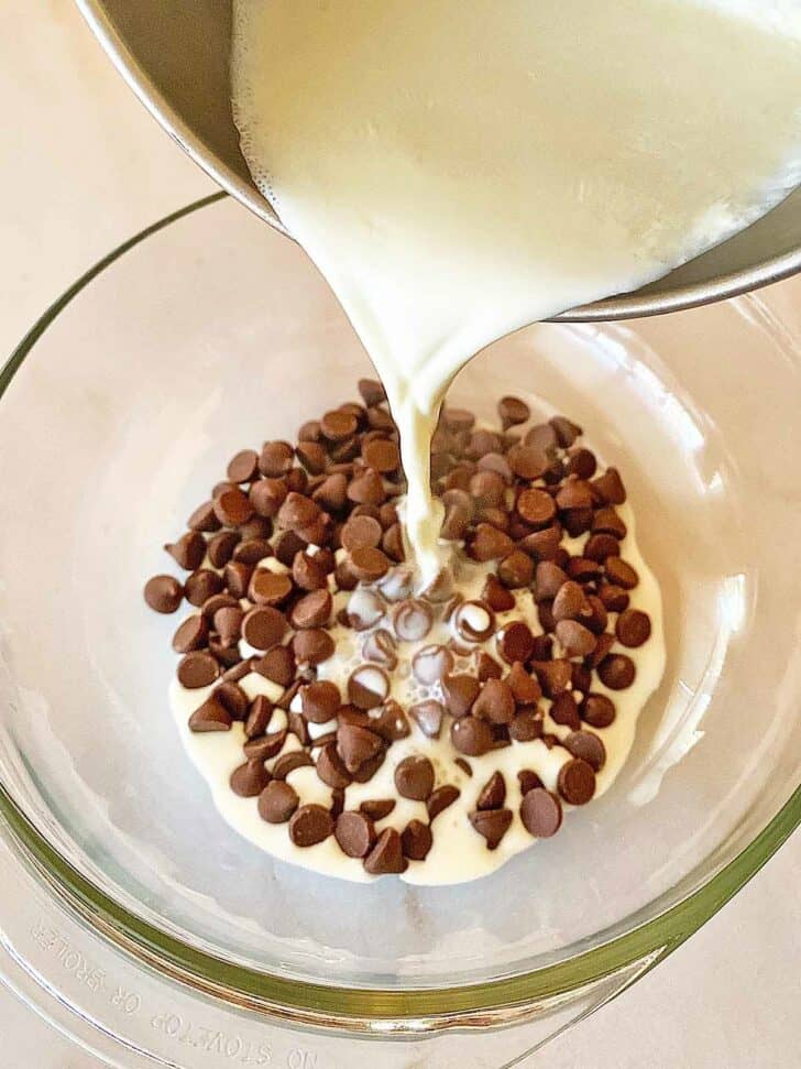 Pouring hot cream over chocolate chips in a bowl.