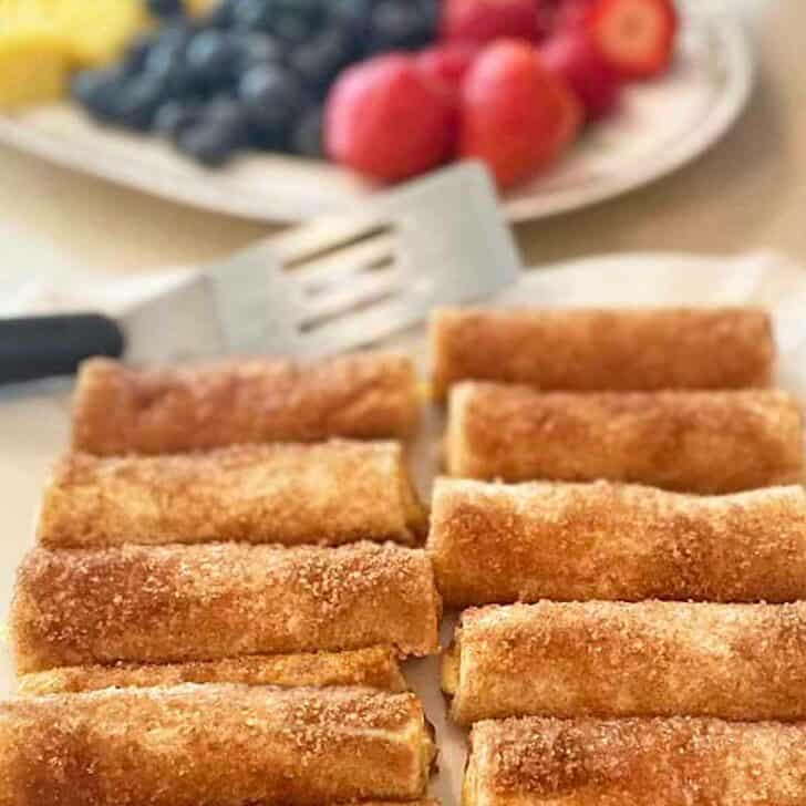 Cinnamon cream cheese rollups on a serving platter with fresh fruit.