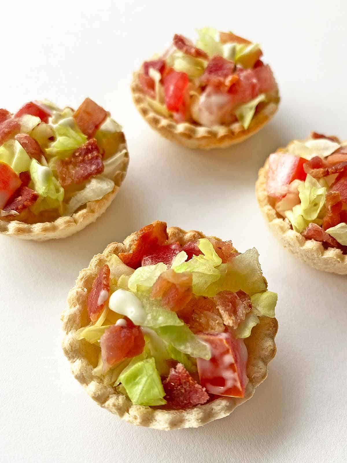 Close up of four BLT cups appetizers on a white background.