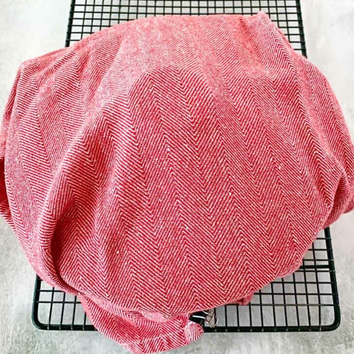 The casserole dish wrapped in a red dish towel.
