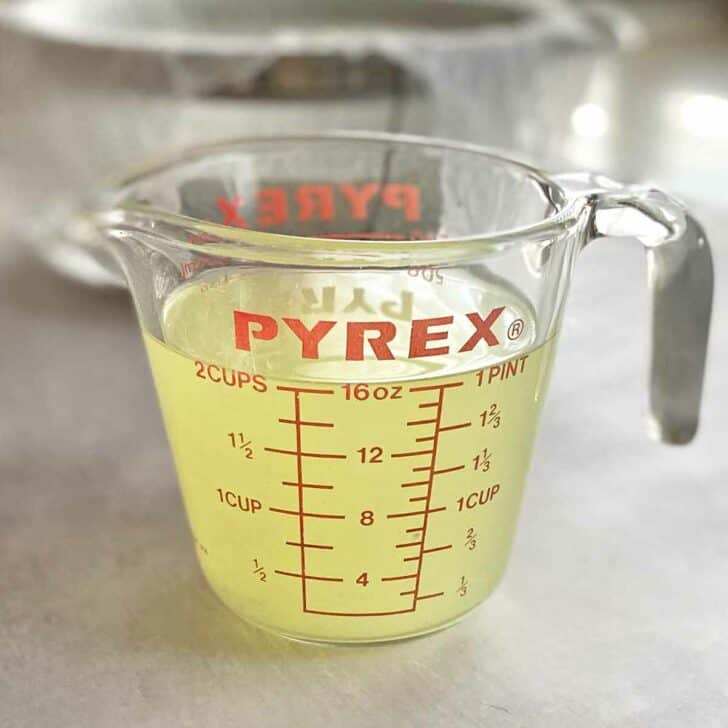 A glass measuring cup filled with whey.
