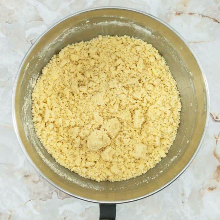 A mixing bowl with the crumb mixture for making crumble cookies.