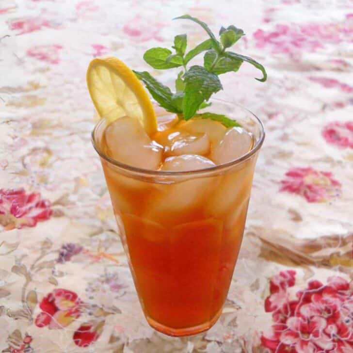 A glass of naturally sweetened iced tea garnished with a lemon slice and fresh mint.