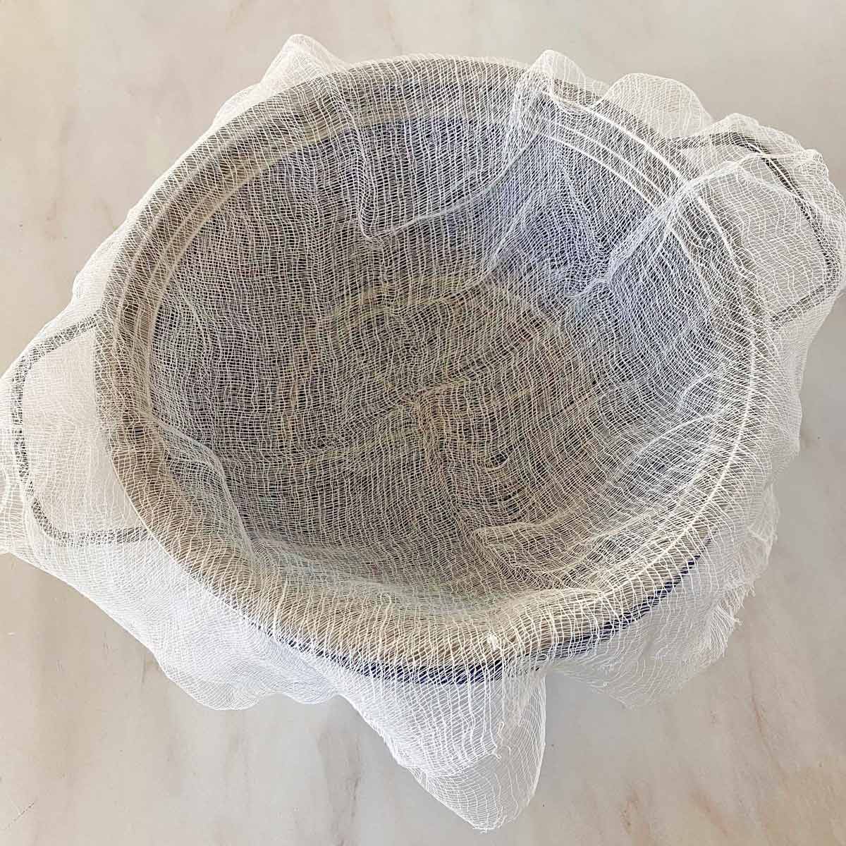 Metal strainer lined with a layer of cheesecloth.