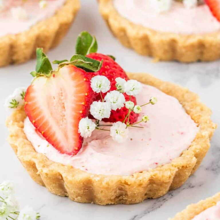 Three mini strawberry tarts with fresh strawberries.