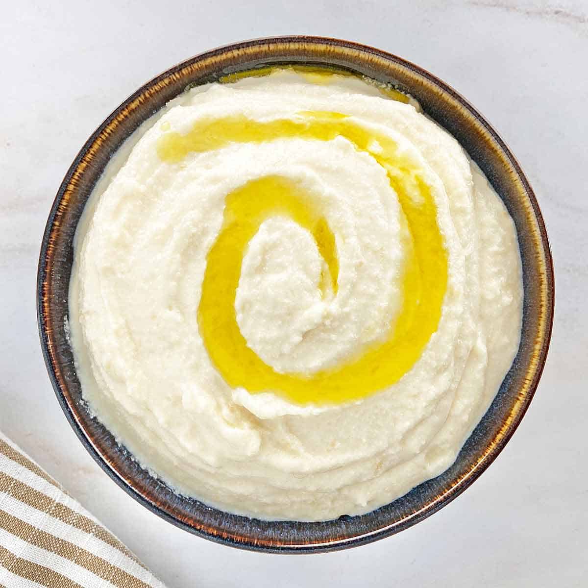 Whipped ricotta cheese dip in a serving bowl drizzled with olive oil.