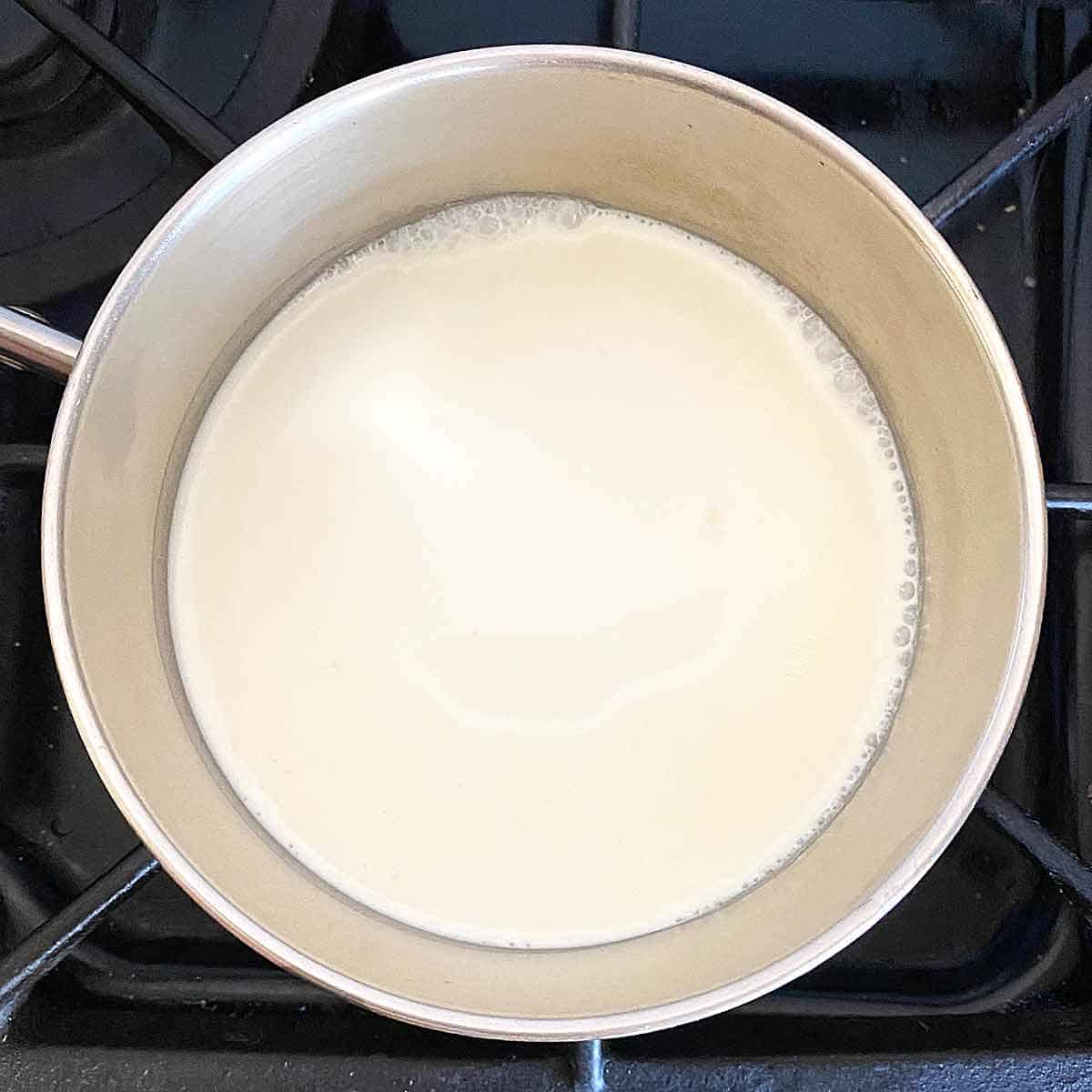Heating cream in a saucepan on the stove.