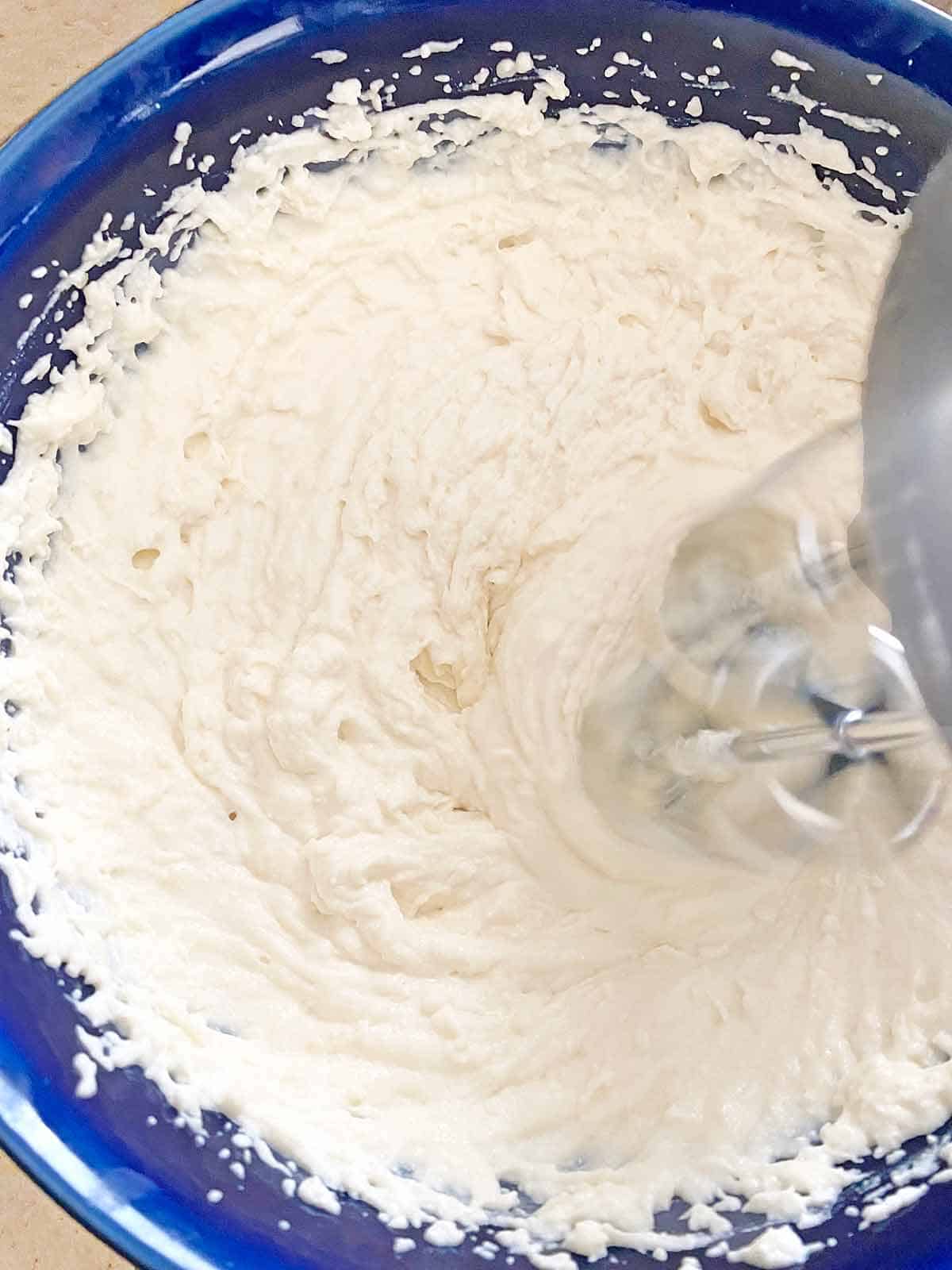 Whipping ricotta cheese with Parmesan cream in a mixing bowl.