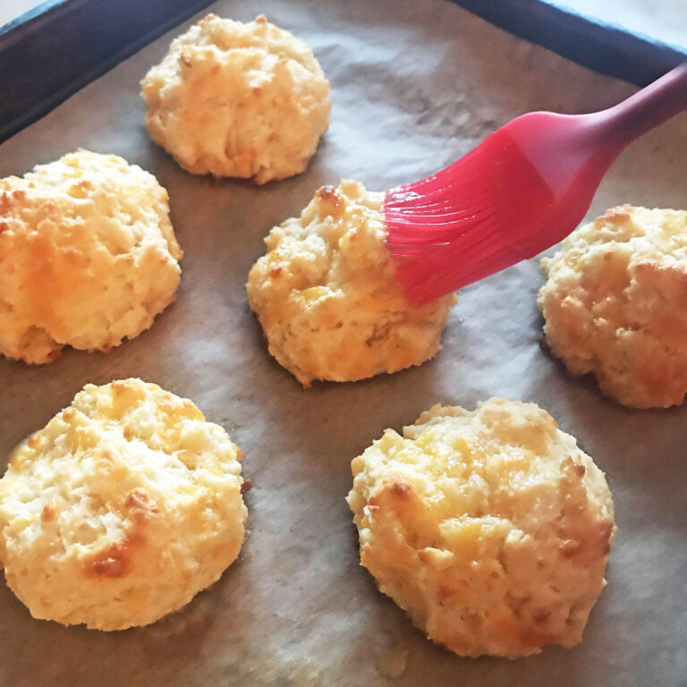 Brushing cheddar drop biscuits with butter