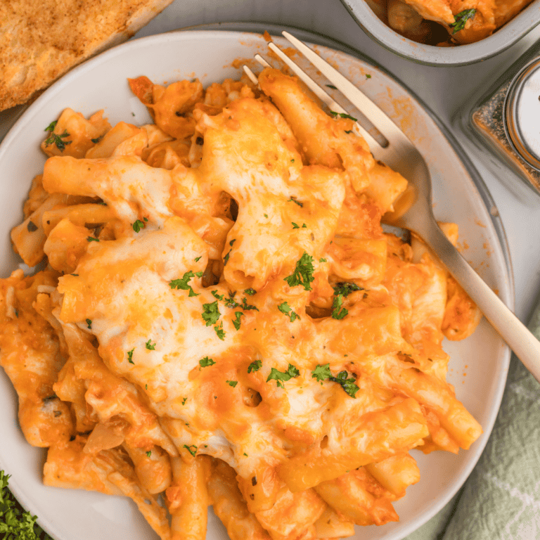 A white dinner plate with a serving of baked ziti.