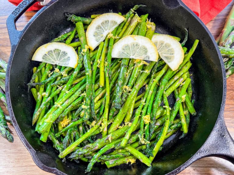 Asparagus and lemon slices in a cast iron pan.