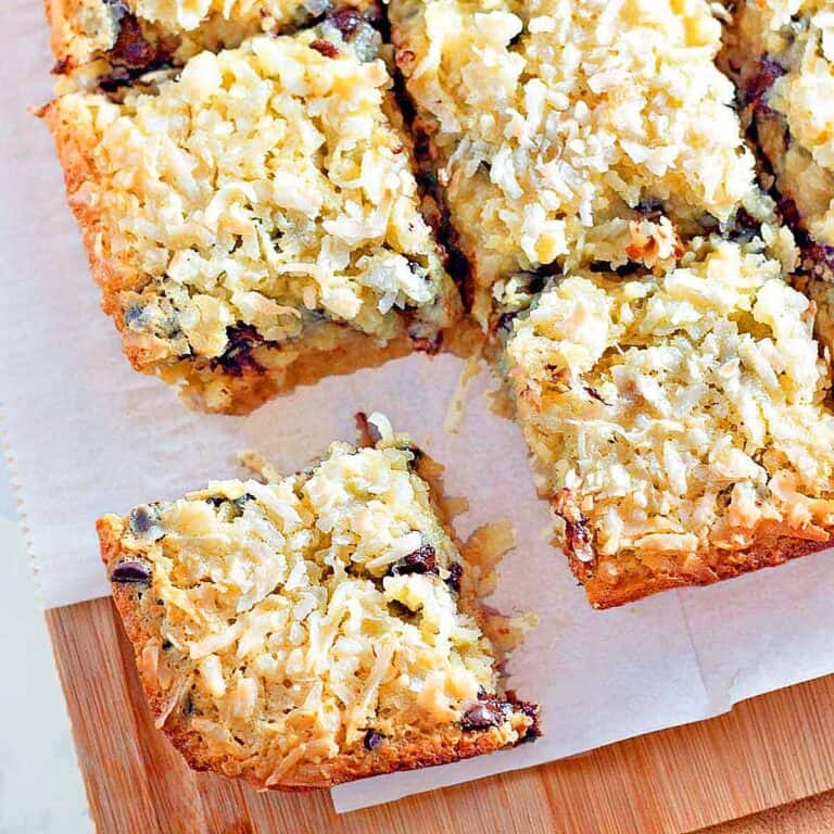 Four coconut chocolate chip cookie bars on a wood cutting board.