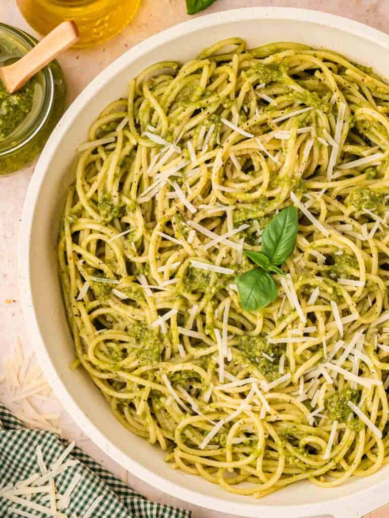 A white serving dish filled with pasta and pesto.