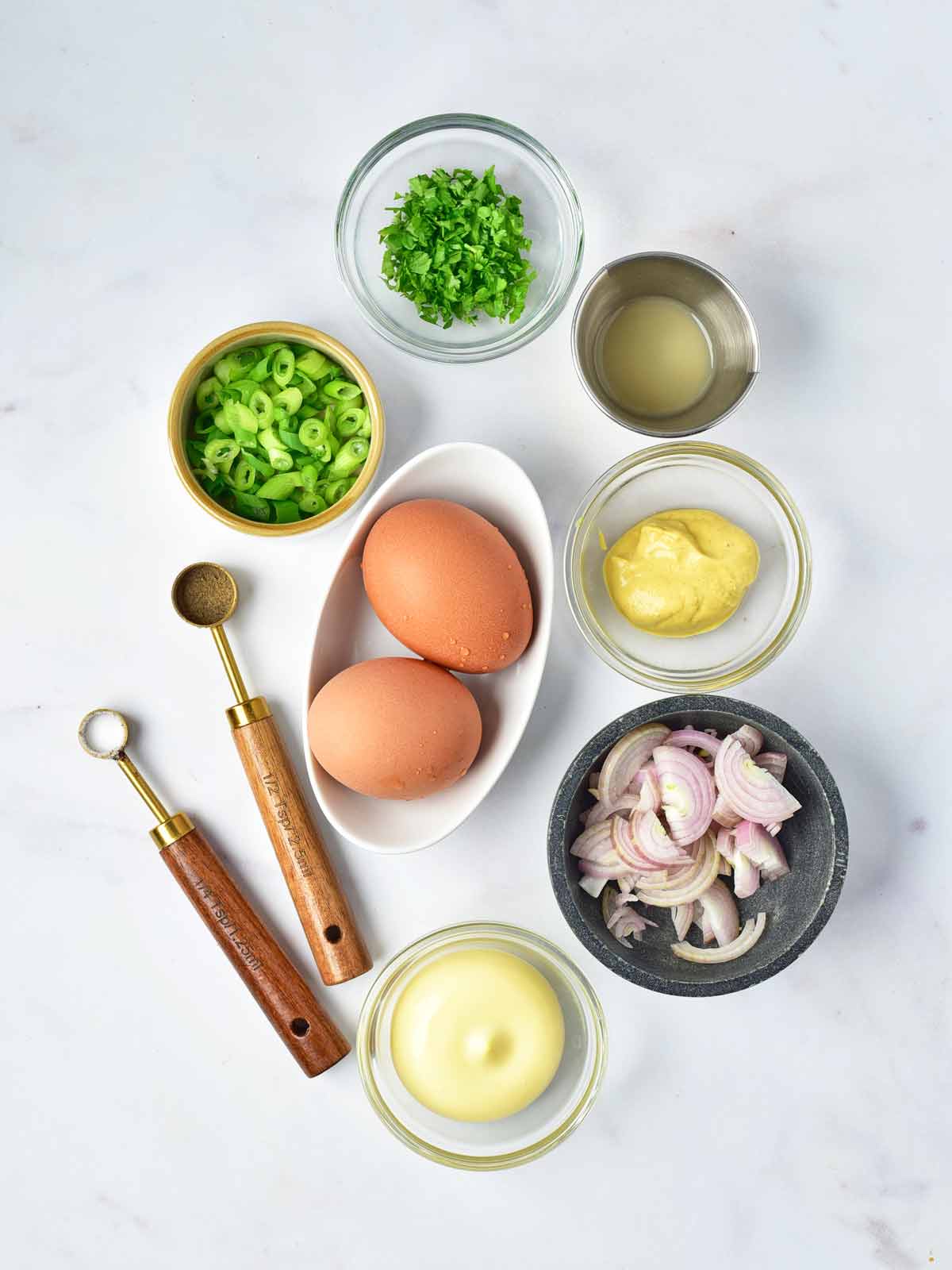 Ingredients needed to make Southern egg salad, including eggs, shallot, mayonnaise, mustard, green onions, parsley, and lemon juice.